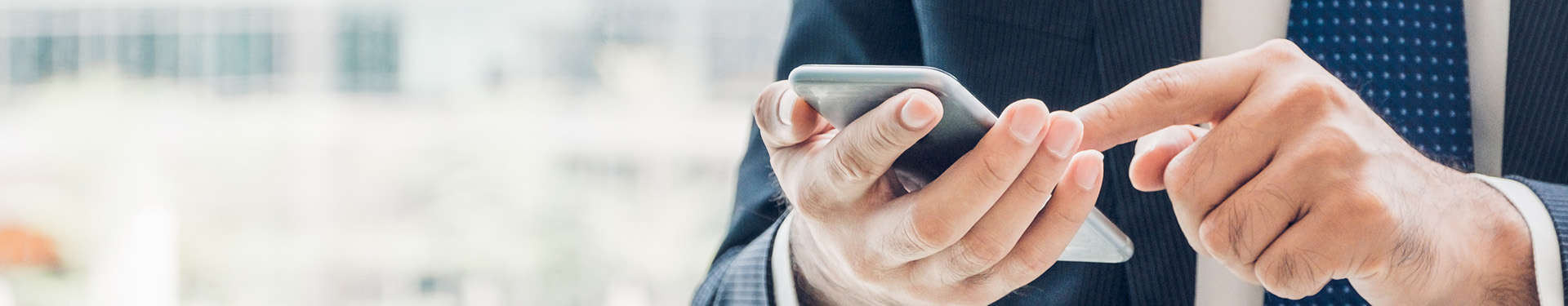 close up hand of businessman using mobile phone near office wind